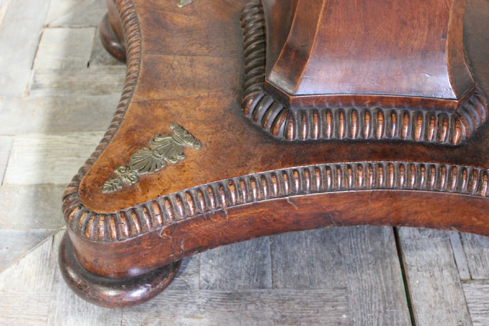 A Regency period pollard oak centre table featuring a rounded rectangular top with drawers, resting on a central pedestal and a shaped quadform base. View III