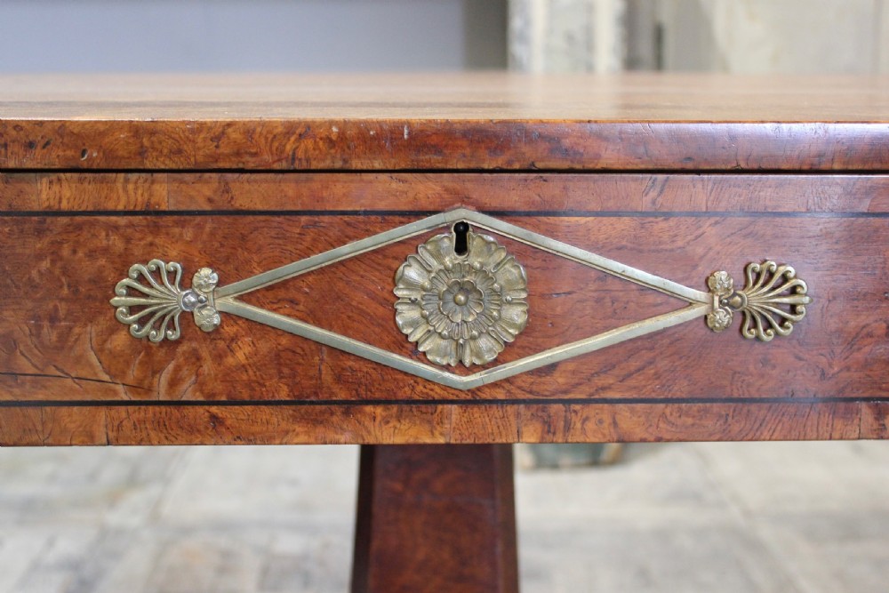A Regency period pollard oak centre table featuring a rounded rectangular top with drawers, resting on a central pedestal and a shaped quadform base. View IV