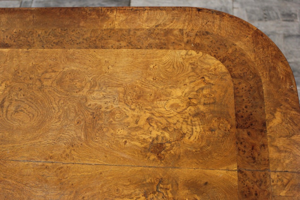 A Regency period pollard oak centre table featuring a rounded rectangular top with drawers, resting on a central pedestal and a shaped quadform base. View VII