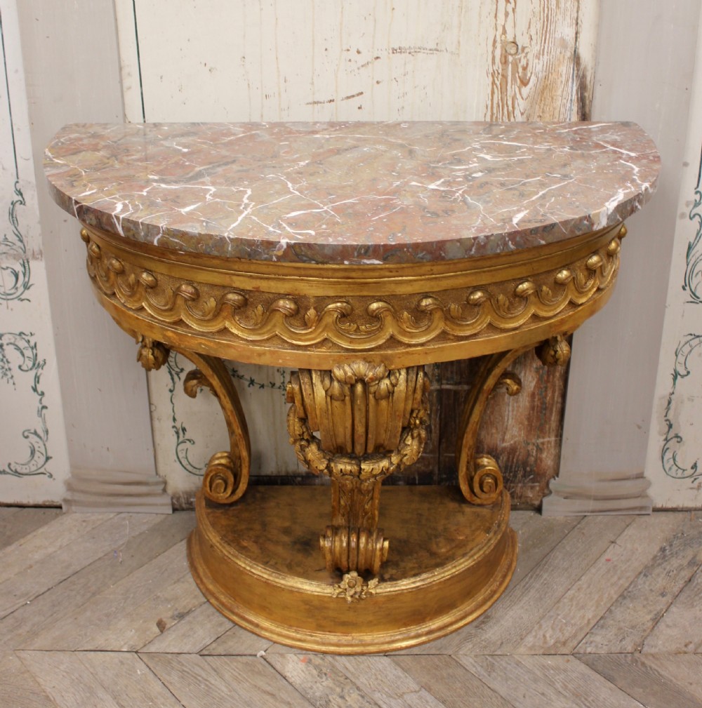 An 18th-century demilune console table featuring a carved giltwood frame with wave frieze detailing and a variegated marble top. View III