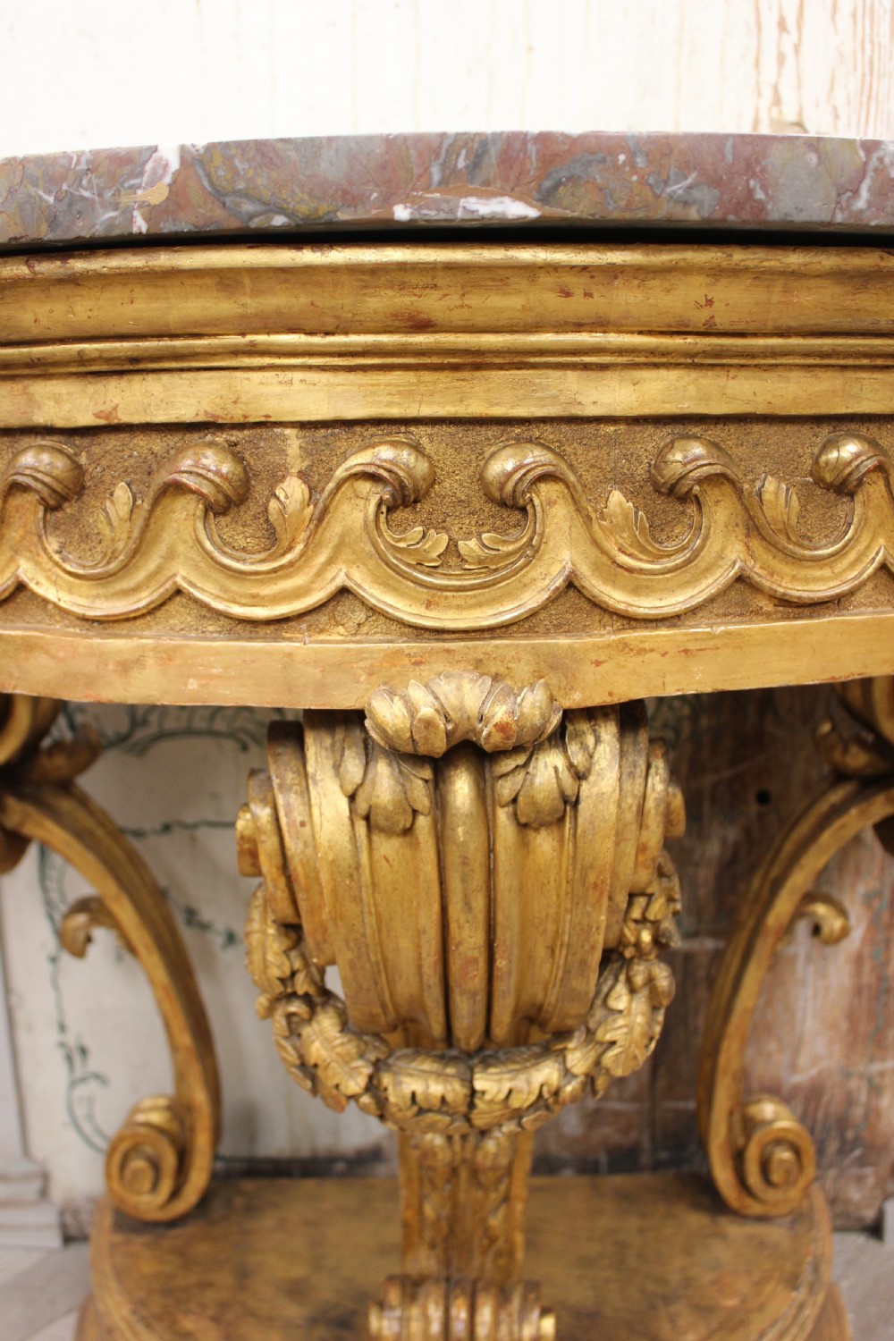 An 18th-century demilune console table featuring a carved giltwood frame with wave frieze detailing and a variegated marble top. View IV