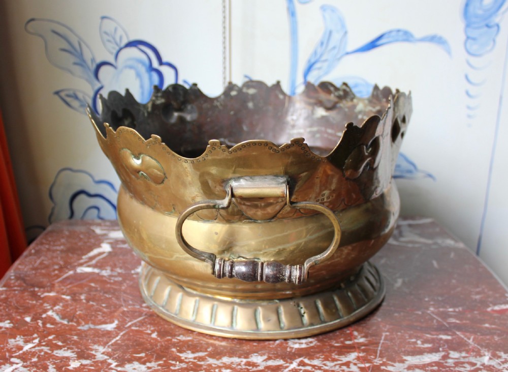 An 18th-century brass monteith bowl featuring a scalloped rim, embossed strapwork motifs, two side loop handles, and a gadrooned foot. View II