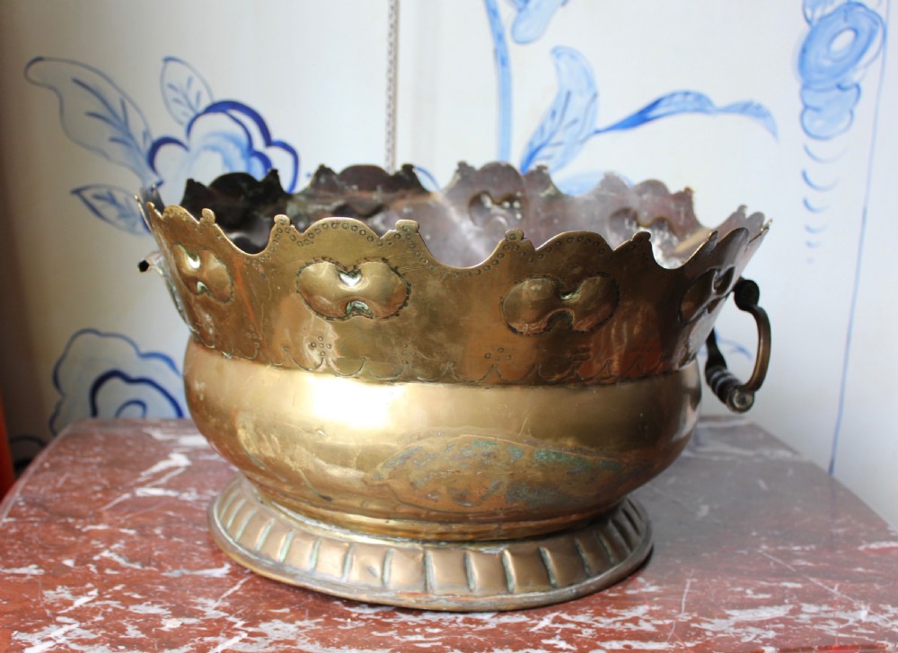 An 18th-century brass monteith bowl featuring a scalloped rim, embossed strapwork motifs, two side loop handles, and a gadrooned foot. View V