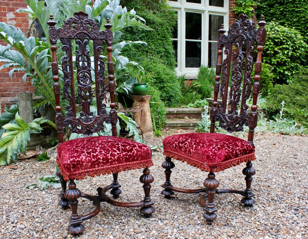 A pair of late 17th-century Baroque side chairs crafted from carved dark walnut with tall pierced backs, red velvet upholstered seats with fringed trim, and turned legs. View II