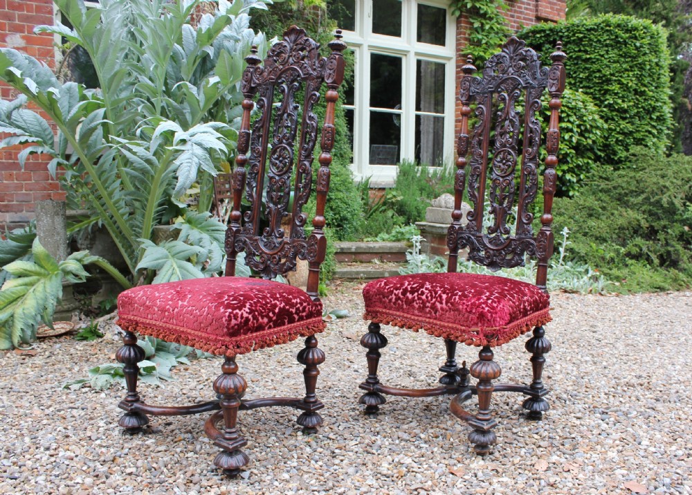 A pair of late 17th-century Baroque side chairs crafted from carved dark walnut with tall pierced backs, red velvet upholstered seats with fringed trim, and turned legs. View III