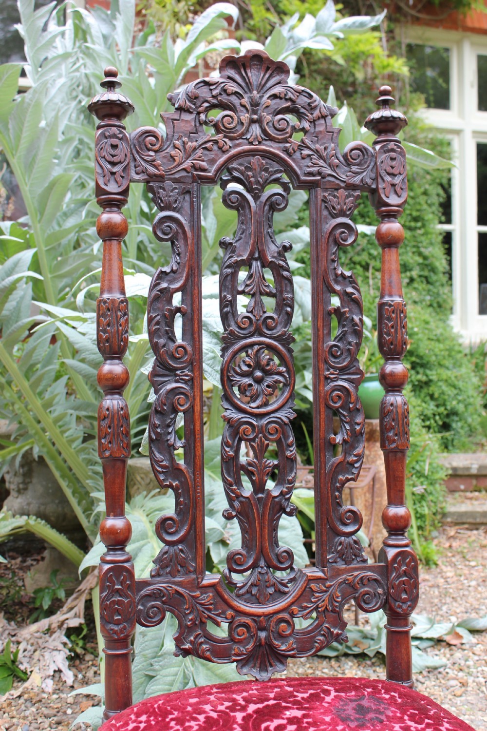 A pair of late 17th-century Baroque side chairs crafted from carved dark walnut with tall pierced backs, red velvet upholstered seats with fringed trim, and turned legs. View IV