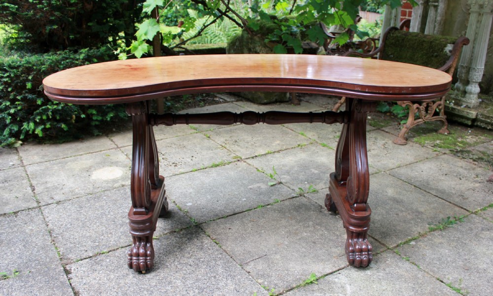 An early 19th-century mahogany kidney-shaped writing table with carved scroll trestle legs, a turned stretcher, and carved claw feet. View II