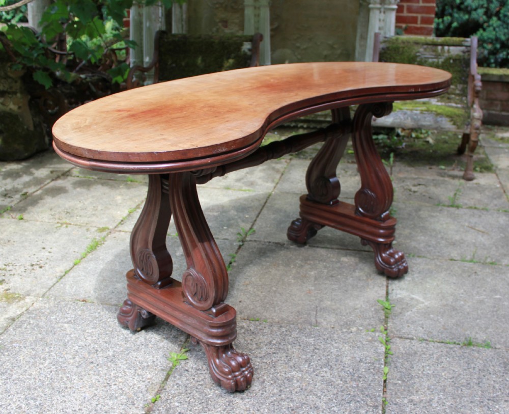 An early 19th-century mahogany kidney-shaped writing table with carved scroll trestle legs, a turned stretcher, and carved claw feet. View V