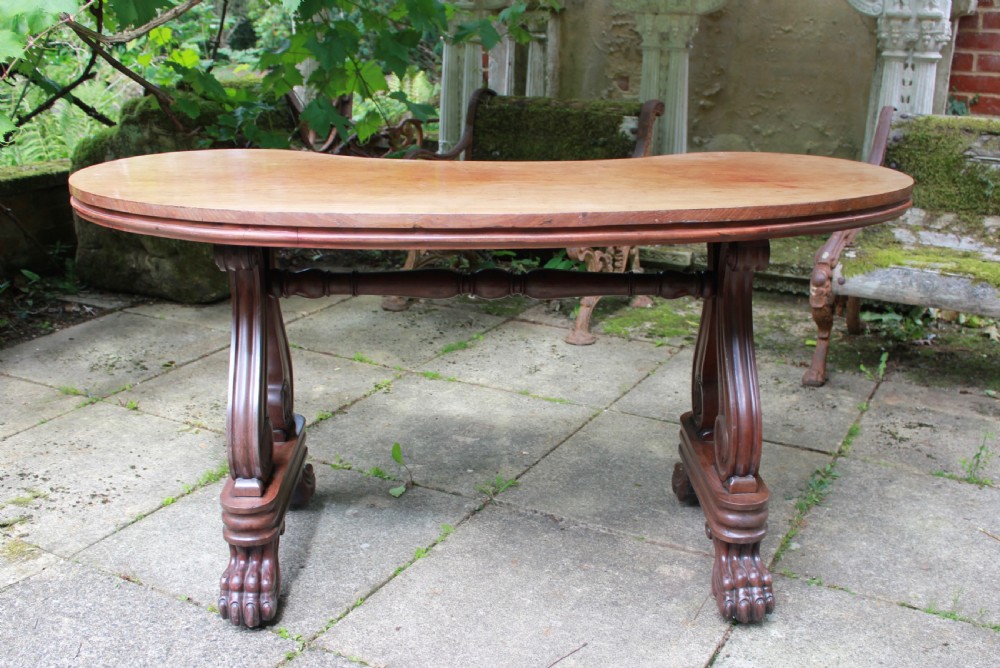 An early 19th-century mahogany kidney-shaped writing table with carved scroll trestle legs, a turned stretcher, and carved claw feet. View VI
