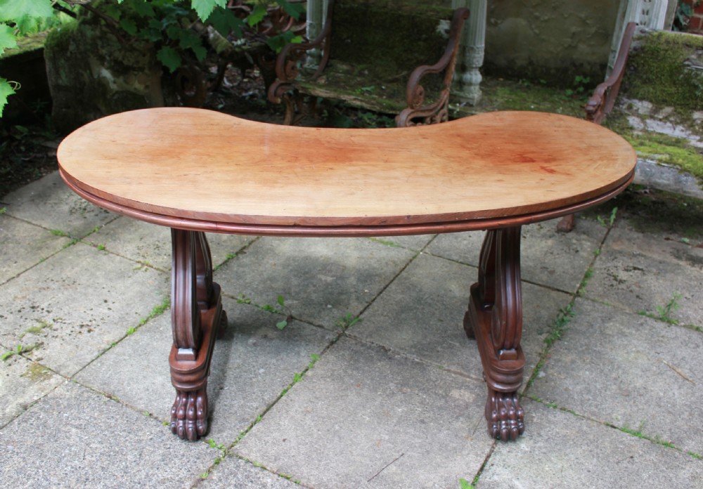 An early 19th-century mahogany kidney-shaped writing table with carved scroll trestle legs, a turned stretcher, and carved claw feet. View VII