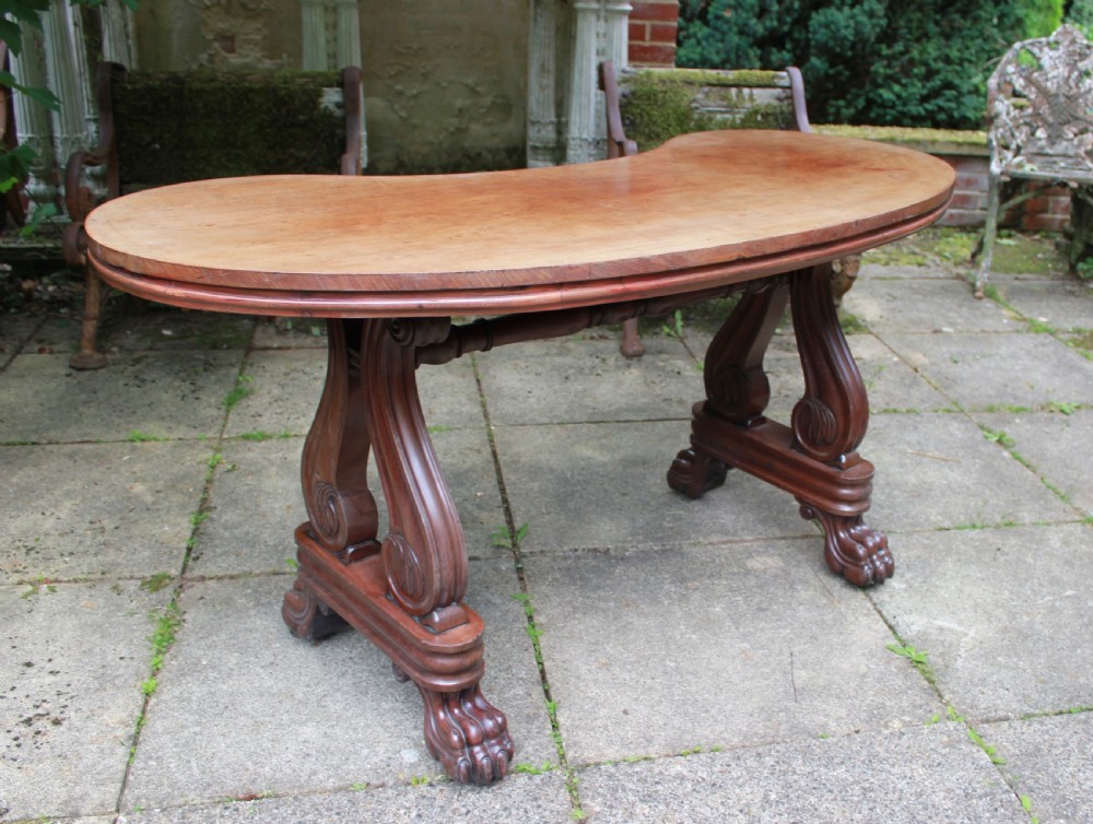 An early 19th-century mahogany kidney-shaped writing table with carved scroll trestle legs, a turned stretcher, and carved claw feet. View VIII