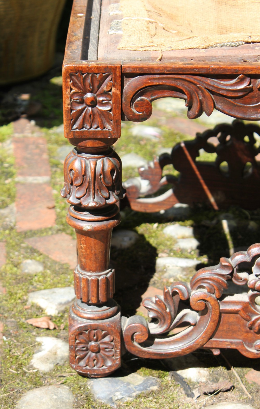 A square dark wood Batavian Baroque stool featuring carved floral aprons, turned baluster legs, pierced stretchers, and a hessian upholstered top. View III