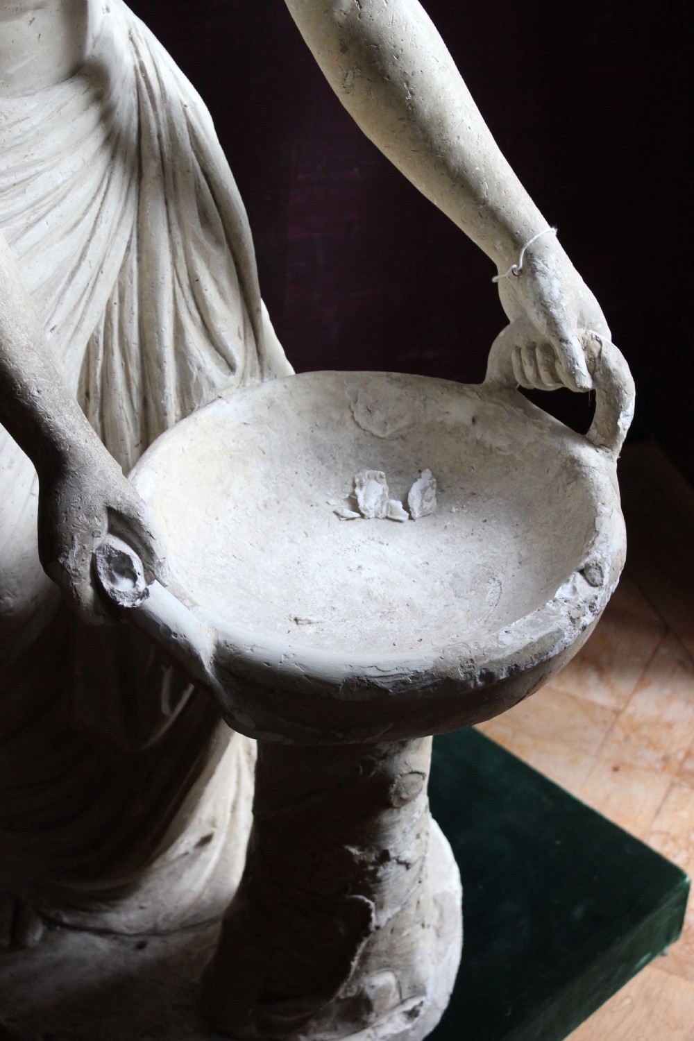 A full-length off-white plaster statue depicting a classical draped female figure standing beside a pedestal basin. View IX