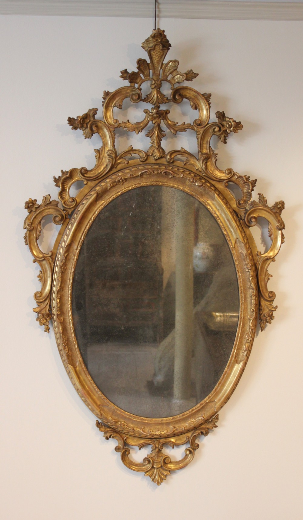 An 18th-century oval wall mirror featuring a carved gold-leaf frame decorated with C-scrolls and acanthus leaves. View II