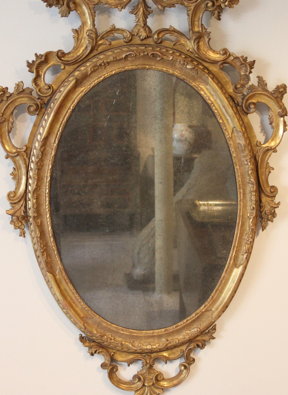 An 18th-century oval wall mirror featuring a carved gold-leaf frame decorated with C-scrolls and acanthus leaves. View III