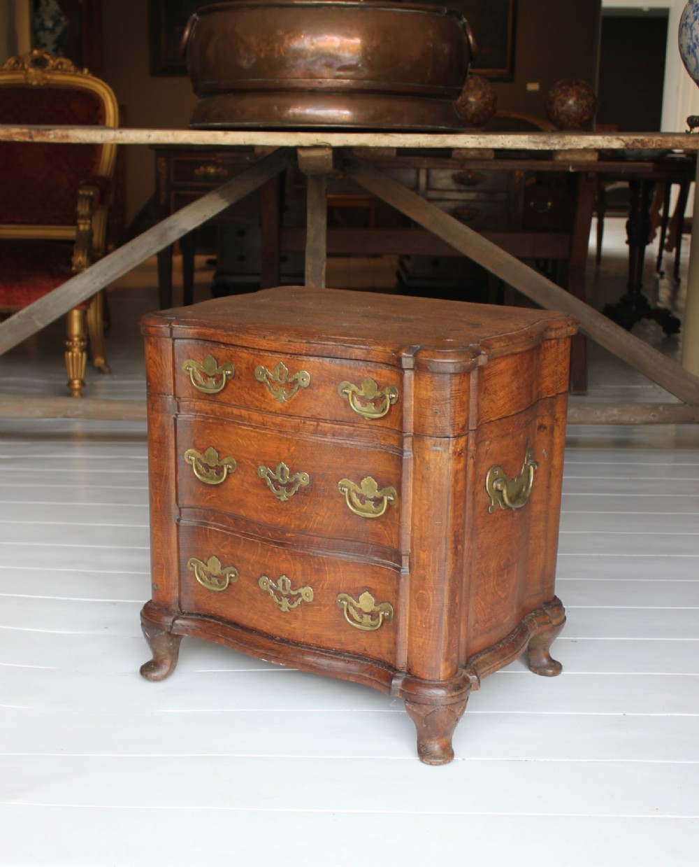 An 18th-century wooden close stool featuring false drawer fronts, brass drop handles, side carrying handles, and short turned feet.