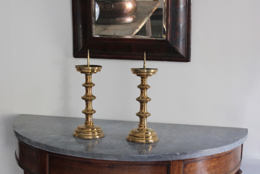 A pair of 16th-century brass pricket candlesticks featuring turned knopped stems and stepped circular bases.