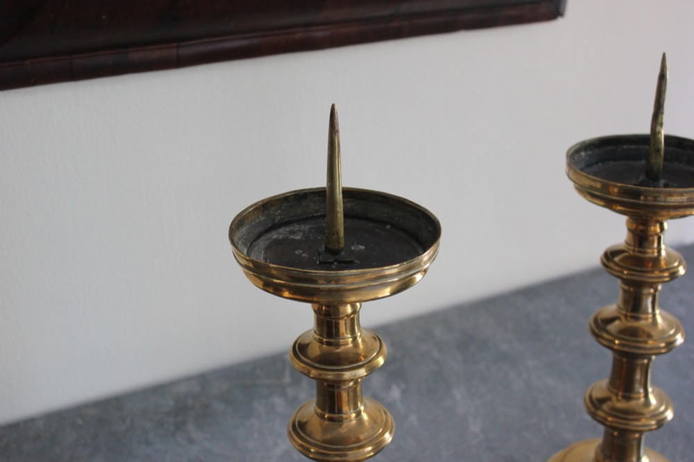 A pair of 16th-century brass pricket candlesticks featuring turned knopped stems and stepped circular bases. View IV