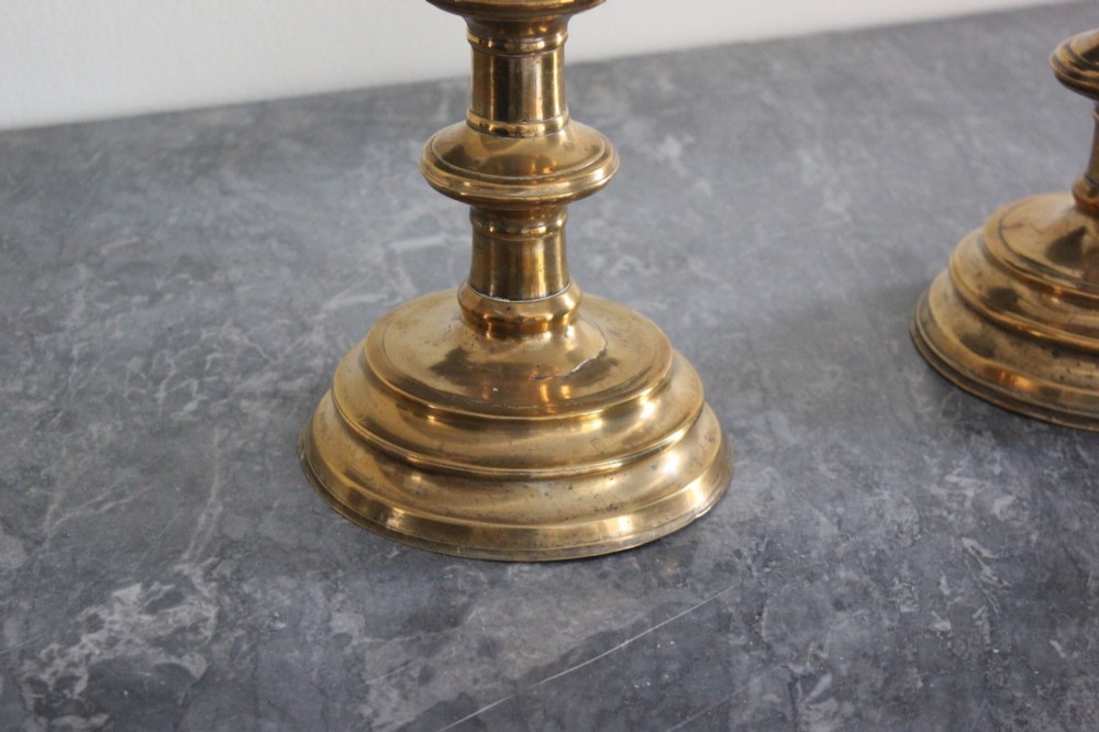 A pair of 16th-century brass pricket candlesticks featuring turned knopped stems and stepped circular bases. View V