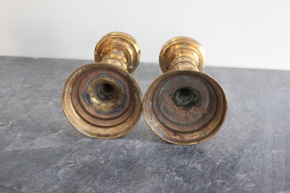 A pair of 16th-century brass pricket candlesticks featuring turned knopped stems and stepped circular bases. View VI