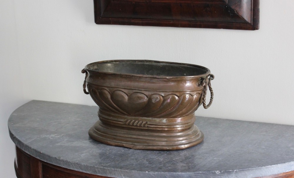 An eighteenth-century oval copper wine cooler with repousse gadrooned detailing, twisted rope side handles, and a stepped base.