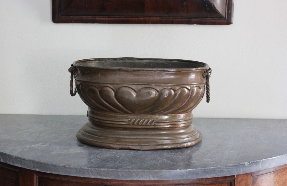 An eighteenth-century oval copper wine cooler with repousse gadrooned detailing, twisted rope side handles, and a stepped base. View II