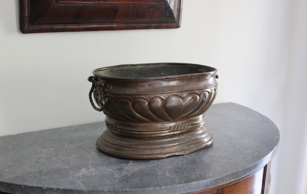 An eighteenth-century oval copper wine cooler with repousse gadrooned detailing, twisted rope side handles, and a stepped base. View III