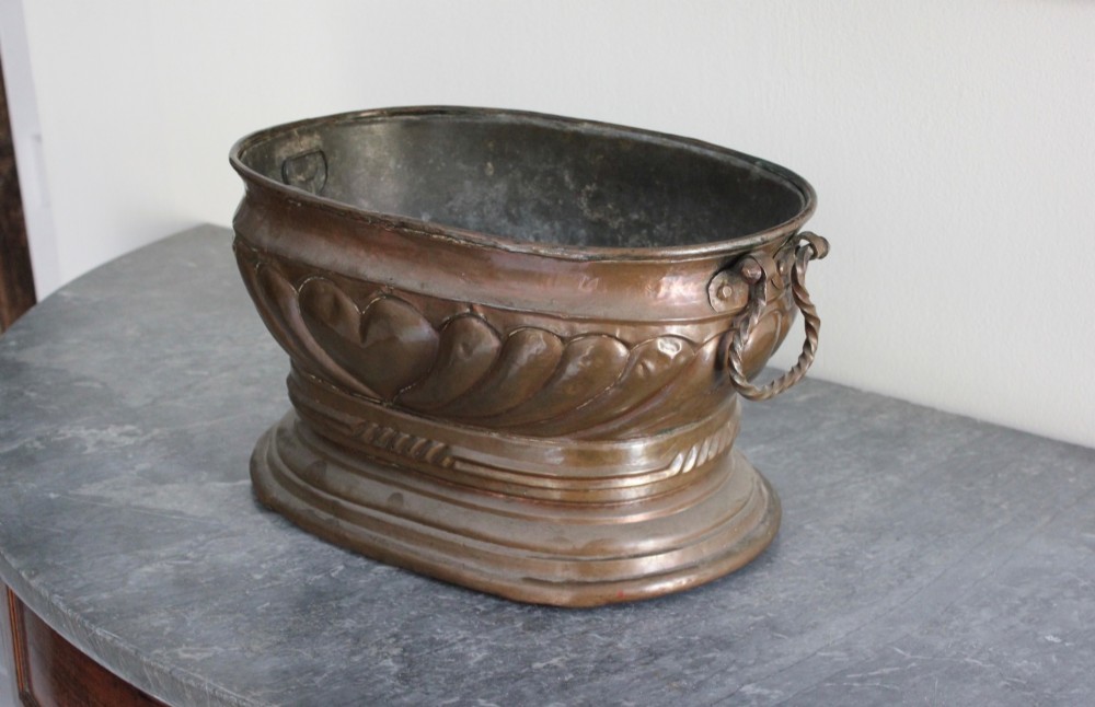 An eighteenth-century oval copper wine cooler with repousse gadrooned detailing, twisted rope side handles, and a stepped base. View IV