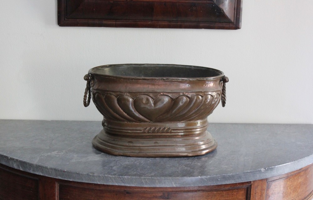 An eighteenth-century oval copper wine cooler with repousse gadrooned detailing, twisted rope side handles, and a stepped base. View V