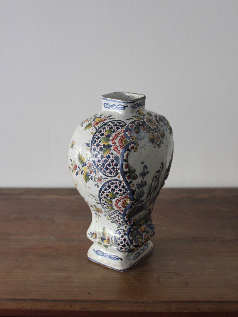 An eighteenth-century off-white tin-glazed ceramic vase decorated with hand-painted polychrome floral motifs across the front. View V