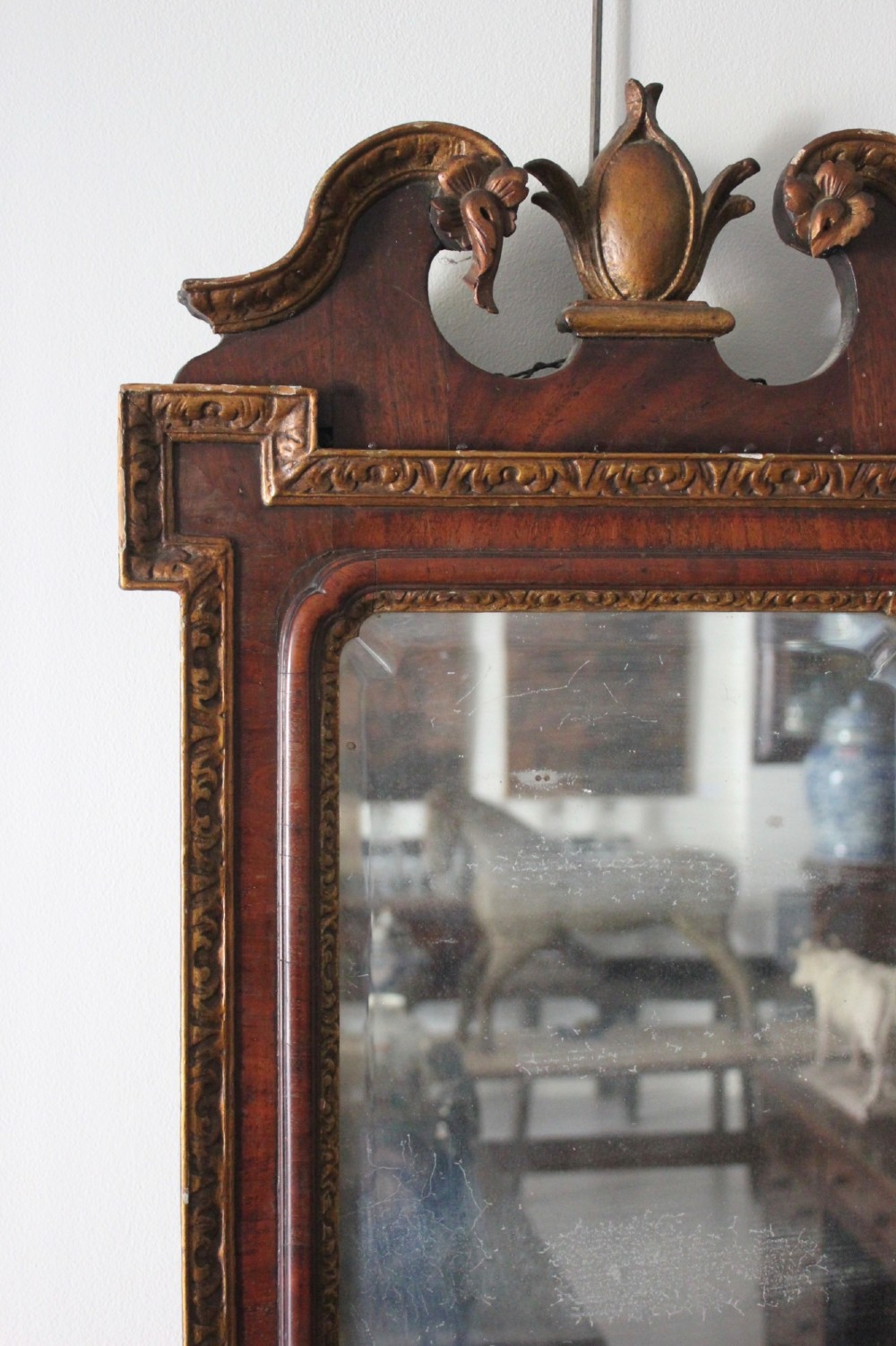 A mid-18th century Georgian mahogany wall mirror featuring a scrolled crested top with a gilded finial and carved slip moulding. View II