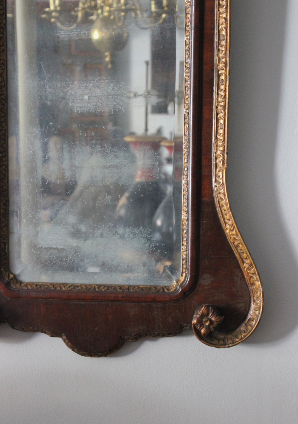 A mid-18th century Georgian mahogany wall mirror featuring a scrolled crested top with a gilded finial and carved slip moulding. View IV