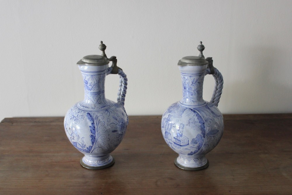 A matched pair of tin-glazed blue and white earthenware ewers featuring pewter hinged lids and twisted handles. View IV