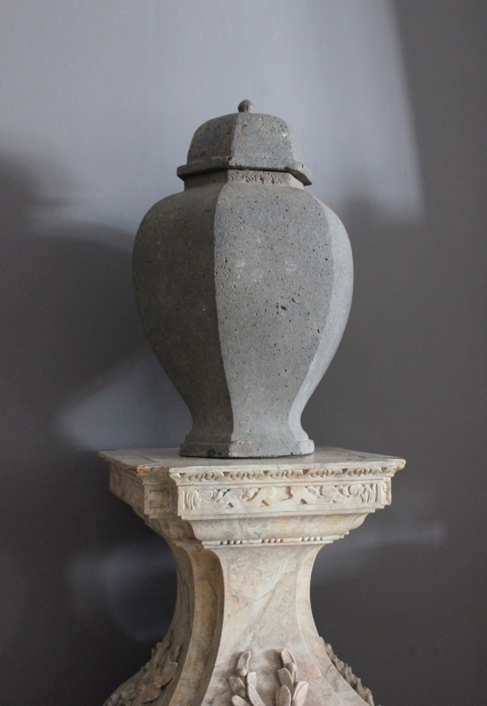 A large grey terracotta lidded urn with a faceted baluster body and textured finish. View II