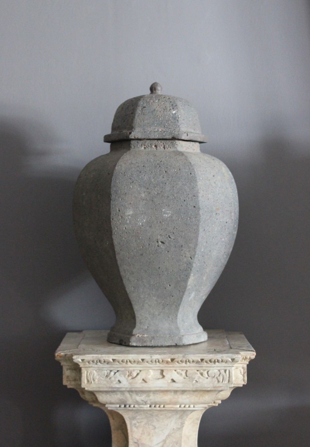 A large grey terracotta lidded urn with a faceted baluster body and textured finish. View III