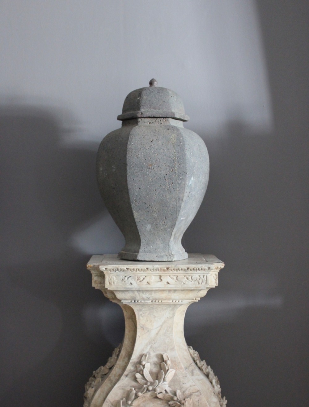 A large grey terracotta lidded urn with a faceted baluster body and textured finish. View IV