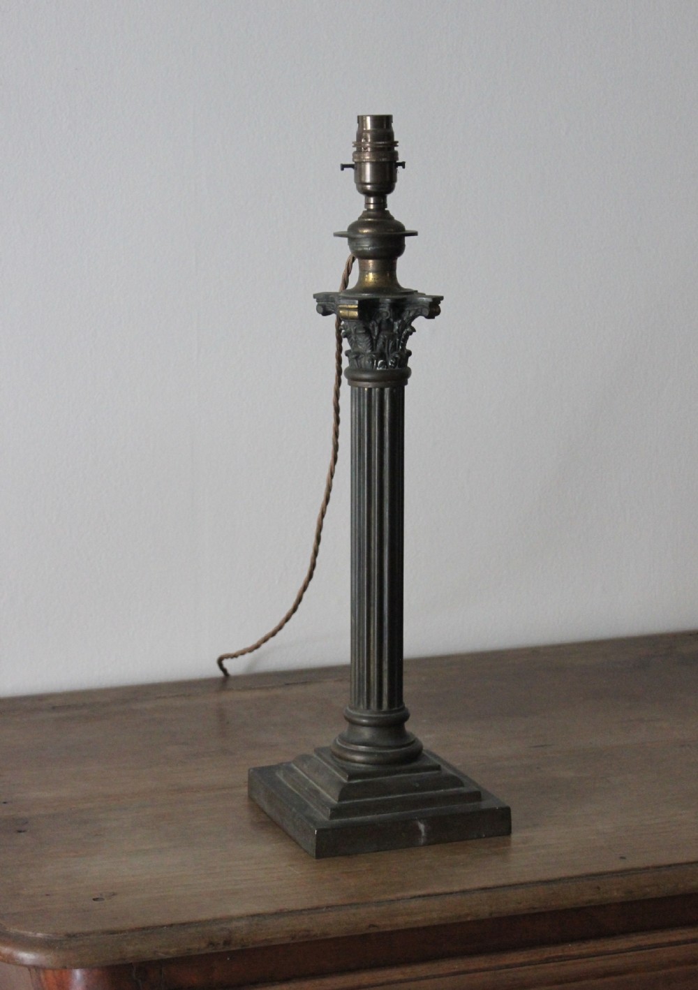 A 19th-century patinated brass table lamp styled as a classical fluted Corinthian column on a square stepped base.