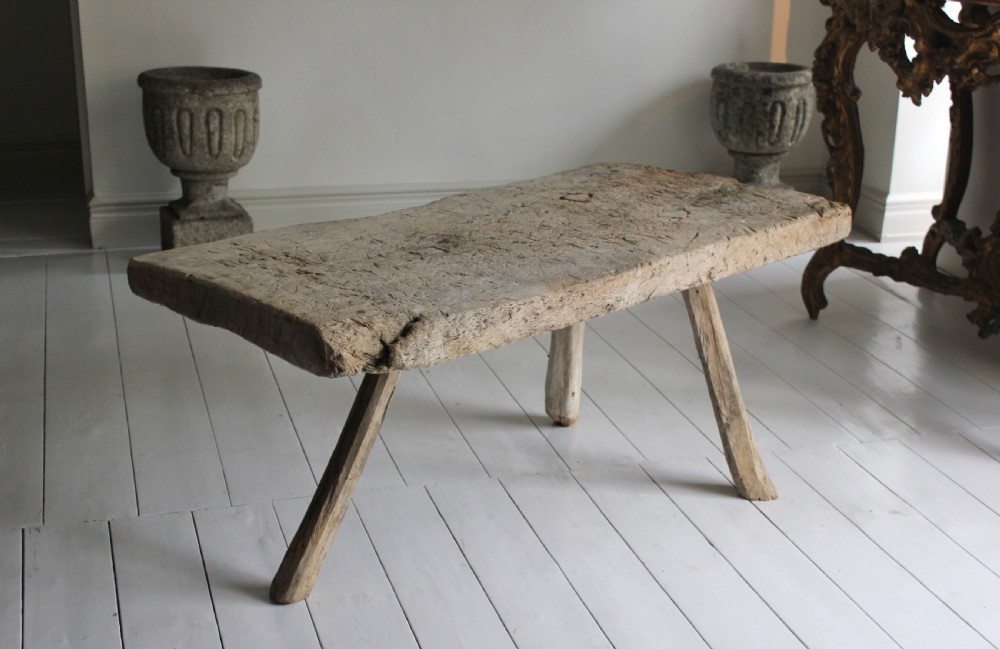 A low 18th-century primitive oak table featuring a thick, heavily weathered slab top resting on four organic, splayed wooden legs. View II