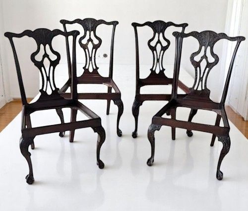 fig 2. A set of four dark mahogany Chippendale style dining chairs featuring carved pierced back splats, mustard velvet seats, and cabriole legs with ball and claw feet.