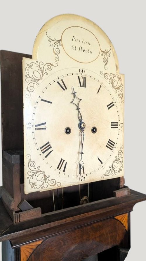 fig 1. A tall Georgian dark wood eight-day longcase clock featuring a swan neck pediment, brass finial, arched dial, and decorative oval inlay on the trunk door and base.