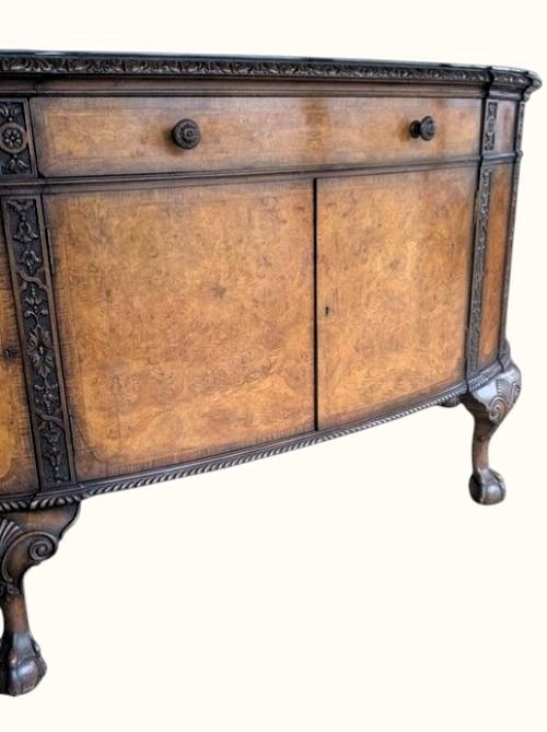 fig 2. A semicircular burr walnut demi-lune sideboard featuring carved cabriole legs with ball-and-claw feet and decorative foliage carvings on the upright pilasters.