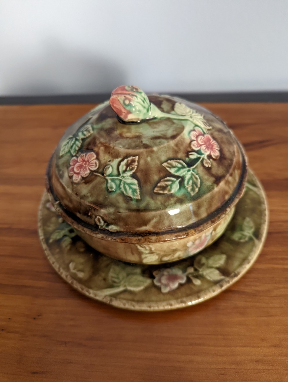 A Victorian majolica lidded dish and matching underplate with relief-moulded rose blossoms, green leaves, a rosebud finial, and a mottled brown glaze. View II