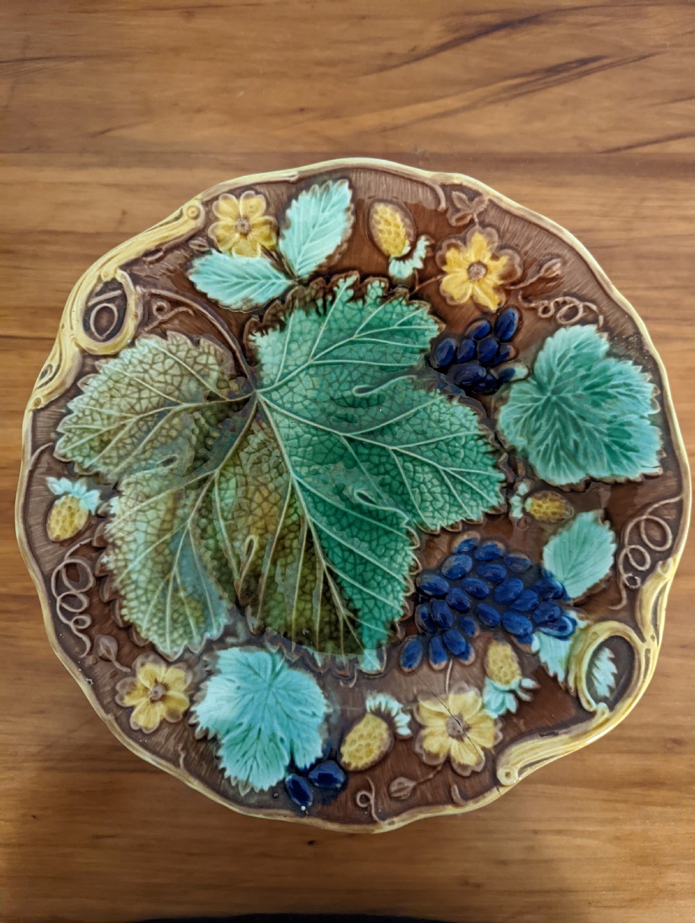 A Victorian majolica pedestal dish featuring moulded green leaves, blue berries, and yellow accents over a brown glazed earthenware surface. View II