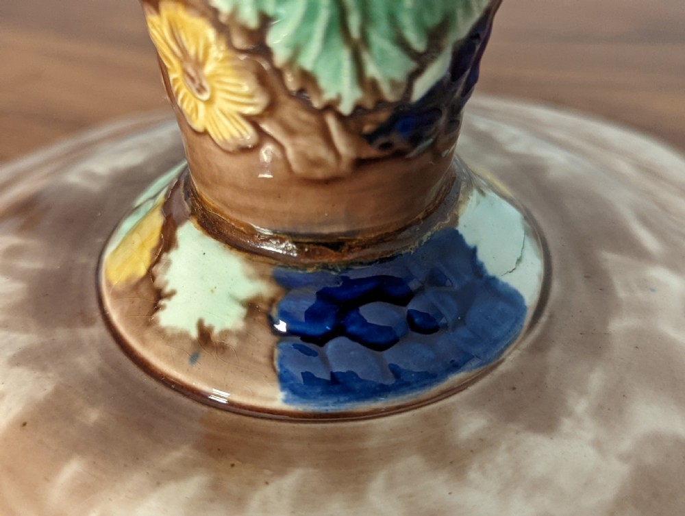 A Victorian majolica pedestal dish featuring moulded green leaves, blue berries, and yellow accents over a brown glazed earthenware surface. View VI