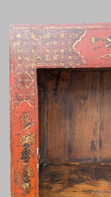 A 19th-century red lacquered Chinese open cabinet featuring hand-painted floral motifs on the outer frame and a central shelf with two small drawers. View IX