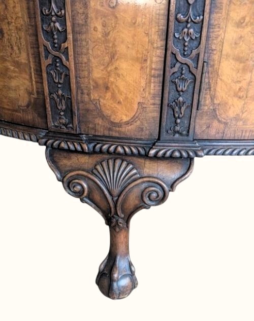 A semicircular burr walnut demi-lune sideboard featuring carved cabriole legs with ball-and-claw feet and decorative foliage carvings on the upright pilasters. View IV