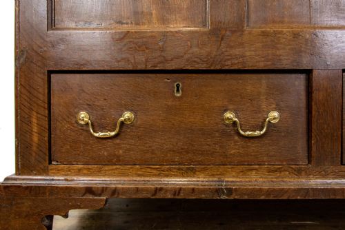 fig 1. An antique dark oak mule chest featuring three recessed front panels, two lower drawers with brass swan-neck handles, and bracket feet.