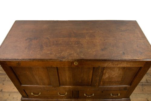 fig 2. An antique dark oak mule chest featuring three recessed front panels, two lower drawers with brass swan-neck handles, and bracket feet.