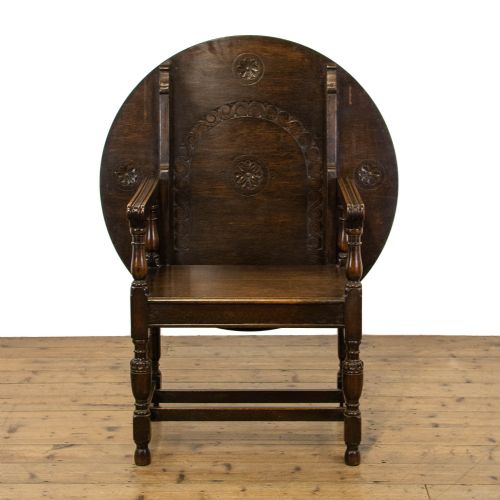 fig 1. A dark oak monks bench featuring a circular carved tilt-top backrest, turned arm supports, and a solid seat raised on turned legs.