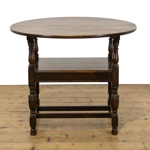 fig 2. A dark oak monks bench featuring a circular carved tilt-top backrest, turned arm supports, and a solid seat raised on turned legs.